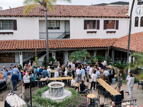 Looking down on the crowd from a balcony at Collen & Christian's Wedding Reception in the courtyard at Frequency Wine Company in Santa Barbara, California
