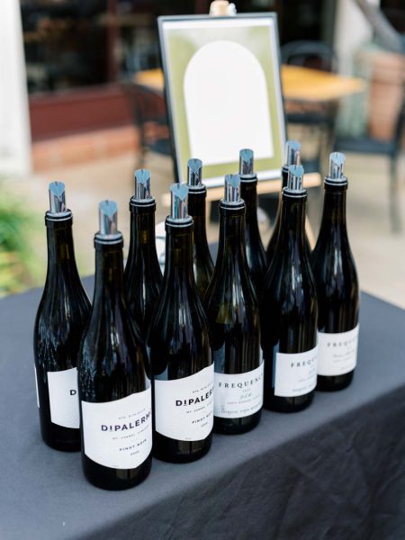 Frequency and DiPalermo wines on a table at Collen & Christian's Wedding Reception in the courtyard at Frequency Wine Company in Santa Barbara, California