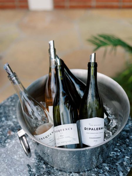 Frequency & DiPalermo wines in an ice bucket at Collen & Christian's Wedding Reception in the courtyard at Frequency Wine Company in Santa Barbara, California